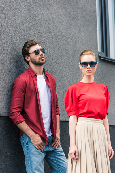 stylish young couple of models in sunglasses posing near building  - Φωτογραφία, εικόνα