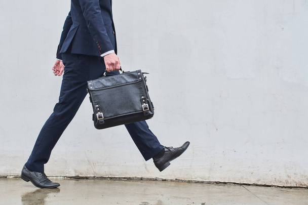  businessman in suit with leather briefcase walking on white wall background  - Foto, Imagen