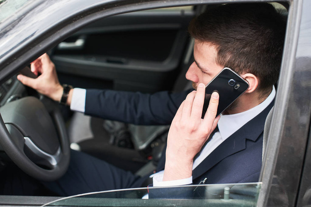 handsome bearded businessman sitting in car and talking on phone  - Zdjęcie, obraz