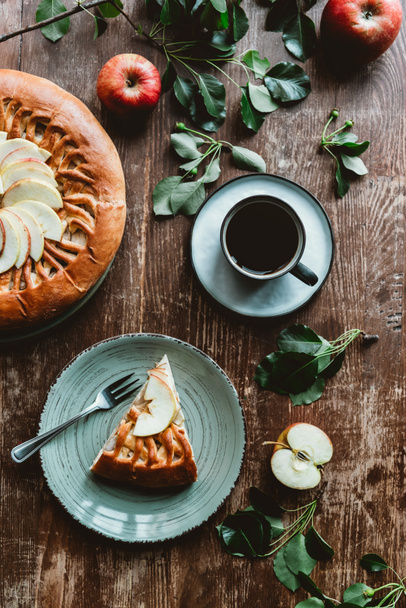 flat lay with cup of coffee, served piece of homemade apple pie on wooden surface - Fotó, kép