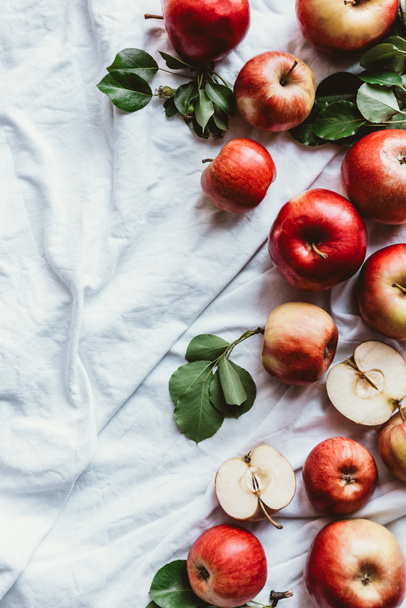 flat lay with fresh apples and green leaves on white linen - Фото, изображение