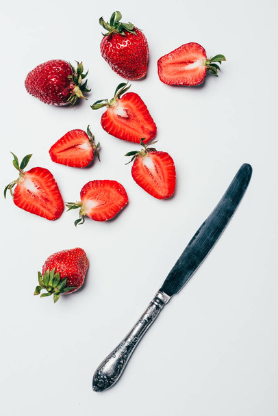 top view of fresh ripe sliced strawberries and knife on white - Фото, зображення