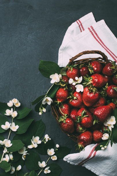 top view of fresh ripe strawberries and beautiful jasmine flowers on black - Foto, Imagen