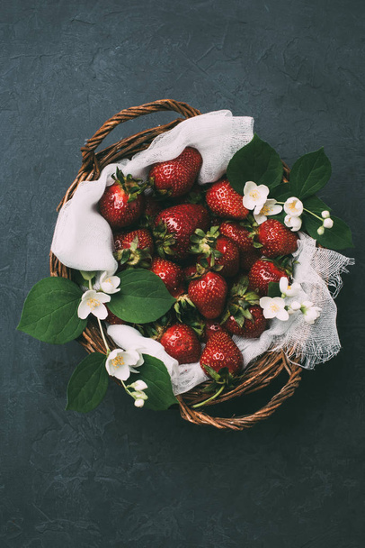 vue de dessus des fraises fraîches mûres et de belles fleurs de jasmin dans le panier sur noir
 - Photo, image