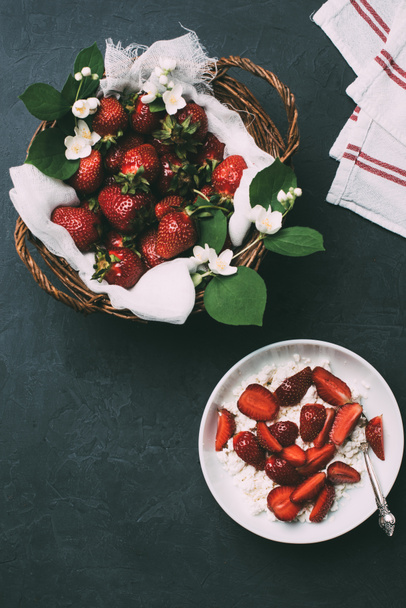 top view of healthy cottage cheese and ripe fresh strawberries on black - 写真・画像
