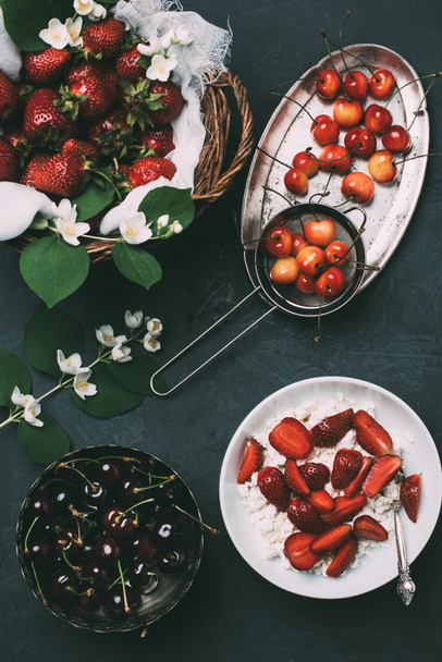 top view of cottage cheese and fresh ripe summer berries on black  - Фото, зображення