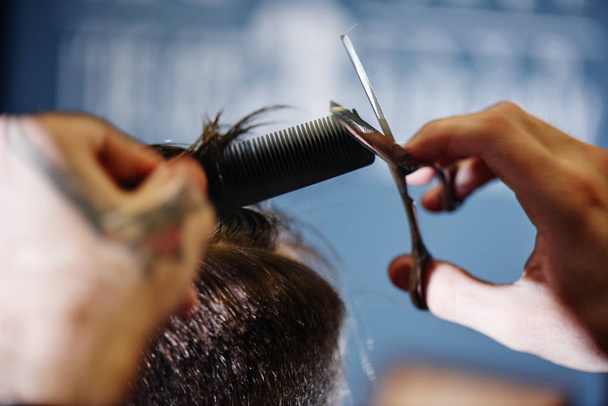 Barber with scissors cutting male hair in Barbershop closeup - Photo, image