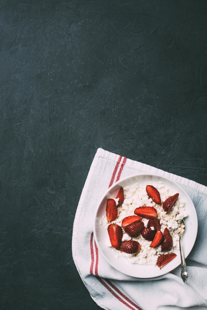 top view of healthy cottage cheese with ripe strawberries on black   - Foto, imagen