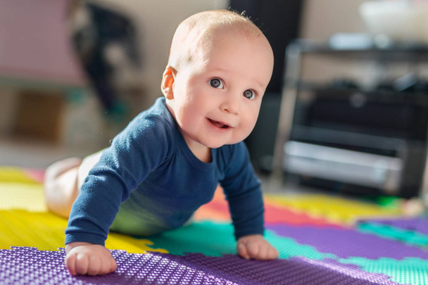 Infant baby boy playing on colorful soft mat. Little child making first crawling steps on floor. Top view from above - Foto, Imagem