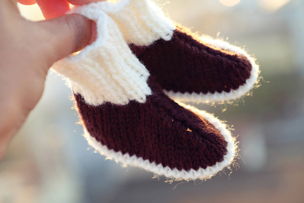 Gebreide baby slofjes voor pasgeboren uit garen, close up van leuke handgemaakte producten voor schoeisel  - Foto, afbeelding