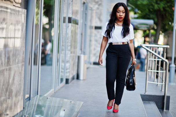 Stylish african american business woman with handbag on streets of city. - Foto, Imagem
