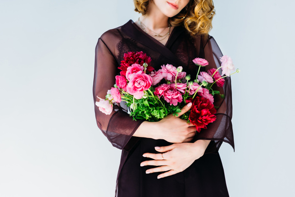 cropped shot of elegant stylish woman holding tender pink flowers isolated on grey - Foto, afbeelding