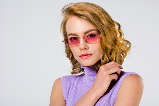 portrait of beautiful young woman in pink sunglasses looking at camera isolated on grey  - Foto, immagini