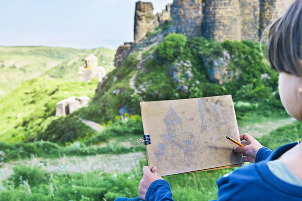 Écolière dessinant une image de l'ancien château d'Amberd au crayon en plein air
 - Photo, image