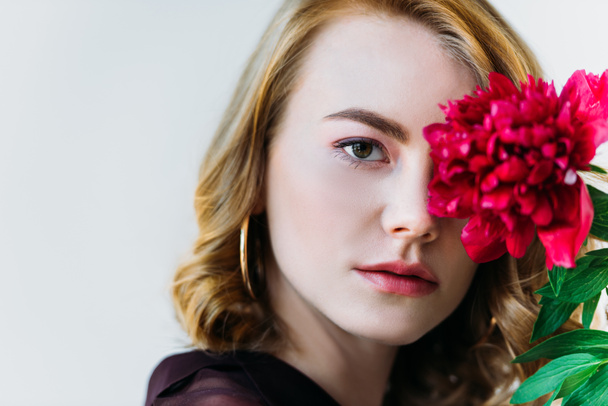 close-up view of girl holding red flower and looking at camera isolated on grey   - Fotografie, Obrázek