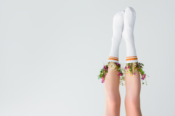 upside down view of female legs with fresh flowers in socks isolated on grey  - Fotó, kép
