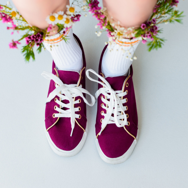 vue en bas des jambes féminines avec des fleurs fraîches dans des chaussettes isolées sur gris
 - Photo, image
