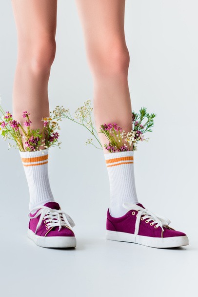 partial view of female legs with beautiful flowers in socks isolated on grey - Fotó, kép