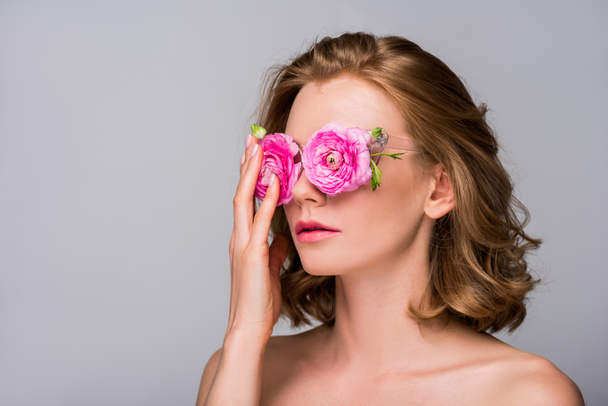 young naked woman adjusting eyeglasses with flowers isolated on grey - Foto, immagini