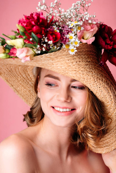 portrait of beautiful smiling naked girl wearing wicker hat with flowers isolated on pink - Φωτογραφία, εικόνα