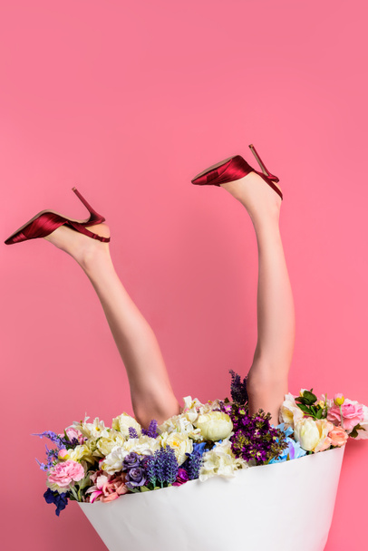 cropped shot of girl in high heeled shoes and skirt with beautiful flowers on pink, upside down view - Photo, Image