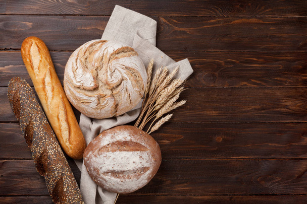 Різні хліб і булочки на дерев'яному столі. Вид зверху з пробілом для вашого тексту
 - Фото, зображення