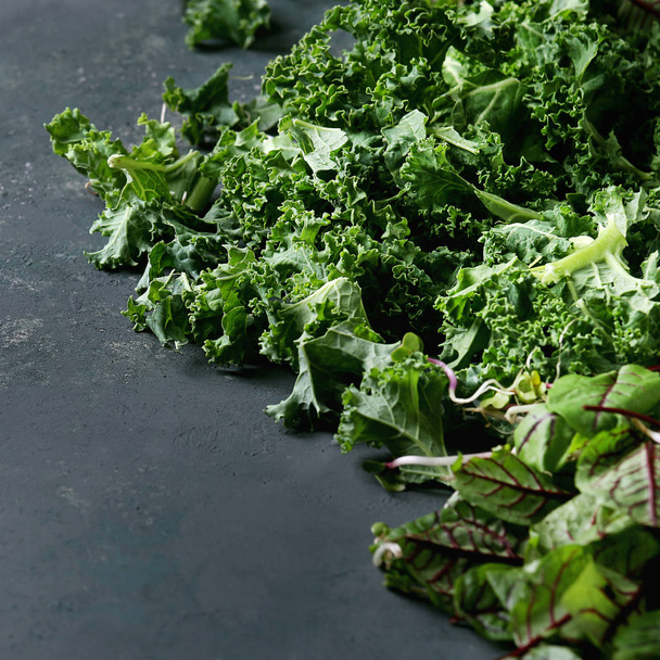 Green salad mix for salad or smoothie with kale, young beetroot leaves, sprouts, over dark texture surface. Copy space. Food background. - Foto, imagen