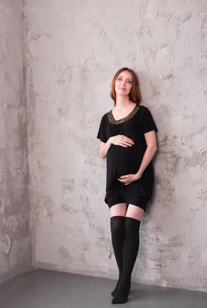 The pregnant girl poses near a wall. Pot-belly of the pregnant woman - Fotó, kép