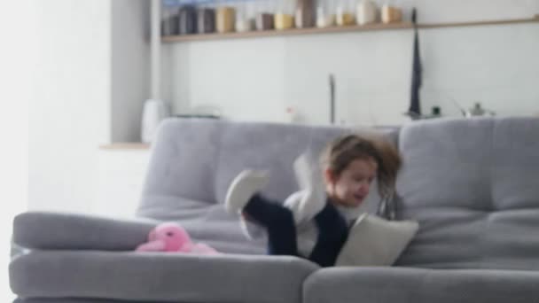 A little girl jumps on the sofa - Imágenes, Vídeo