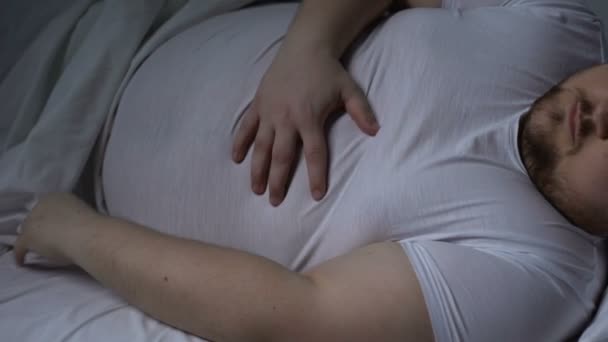 Sick overweight man in bed massaging stomach, health body care, acid reflux - Filmagem, Vídeo