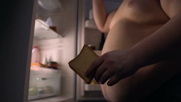 Viciado em fast food homem gordo comer sanduíche e beber cerveja perto da geladeira
 - Filmagem, Vídeo