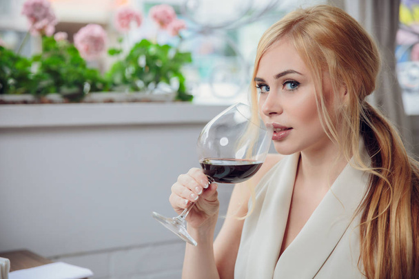 leisure, drinks, degustation, people and holidays concept - beauriful blonde woman drinking red wine at restaurant - Fotoğraf, Görsel