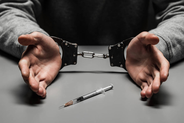 El drogadicto fue arrestado por consumir drogas en la mesa. sufre de adicción sobre un fondo negro oscuro
 - Foto, Imagen