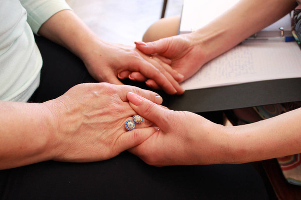 Two girls hold each other's hands during a training course. two girls hold hands on a course on teaching esoteric techniques. friendly support and mutual study of beliefs. - Photo, Image