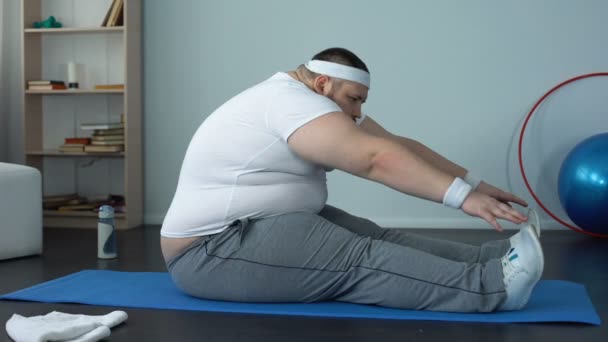 Obese male stretching on mat after home workout, muscle tone, body flexibility - Video, Çekim