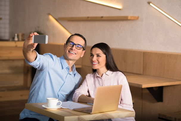 portrait of happy businesspeople taking selfie on smartphone in cafe - Foto, Imagen