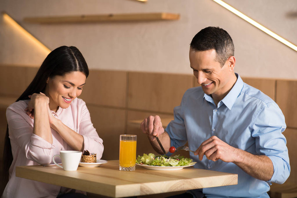smiling businessman and businesswoman having lunch in cafe together - Photo, Image