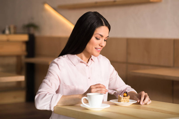 portrait of attractive businesswoman eating cake with coffee in cafe - Foto, afbeelding