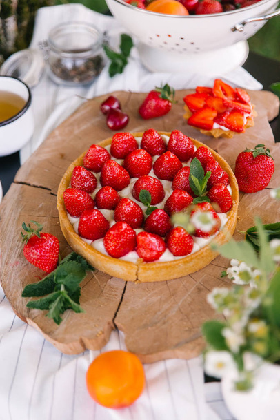 Κλείσιμο προβολής φράουλα κέικ σερβίρεται με λίγη φράουλα τάρτες και τσάι για κομμένο ξύλο σκάφους - Φωτογραφία, εικόνα