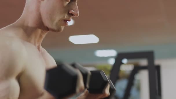 A man is training with dumbbells in the gym - Footage, Video