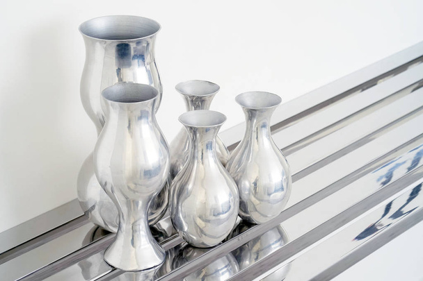 Aluminum vase. A set of aluminum vases on an iron chrome table on a white background. - Zdjęcie, obraz