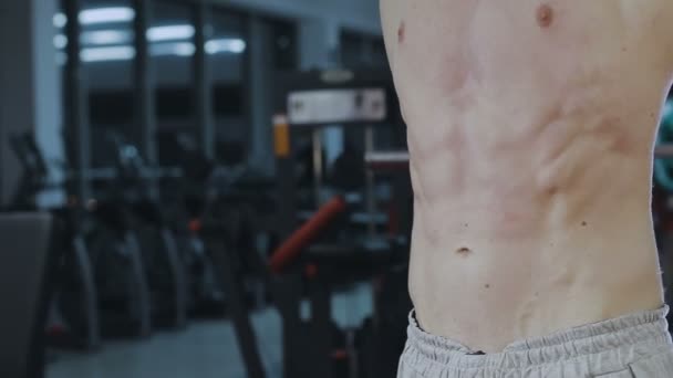 El hombre muestra los músculos abdominales después del entrenamiento en el gimnasio
 - Imágenes, Vídeo
