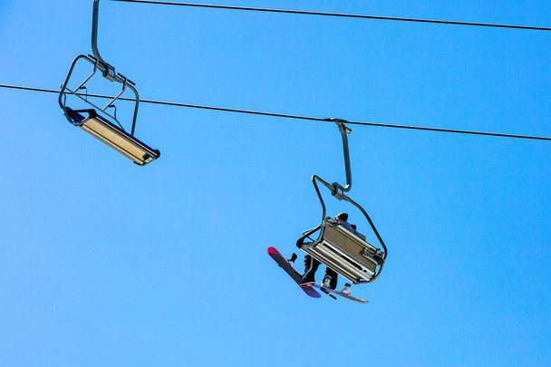 Ski lift with seats going over the mountain and paths from skies and snowboards - Photo, Image