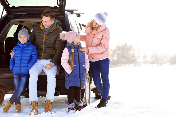 Happy family near car on winter day - Foto, afbeelding