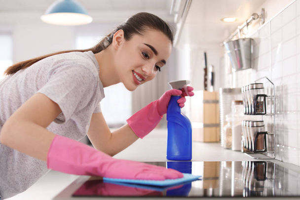 Młoda kobieta czyszczenia piec szmatą w kuchni - Zdjęcie, obraz