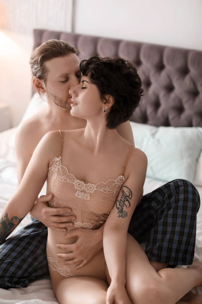 Lovely young couple being intimate on bed at home - Fotó, kép