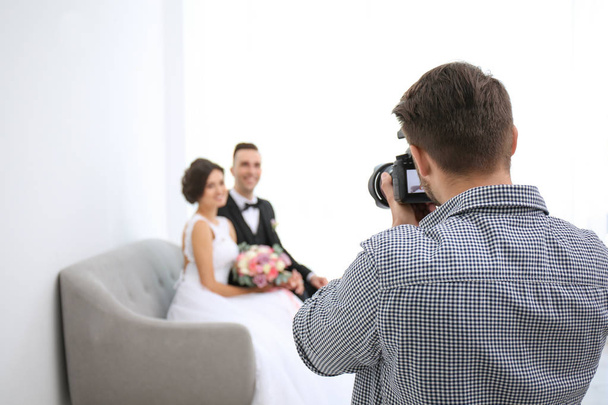 Professional photographer taking photo of wedding couple in studio - Φωτογραφία, εικόνα