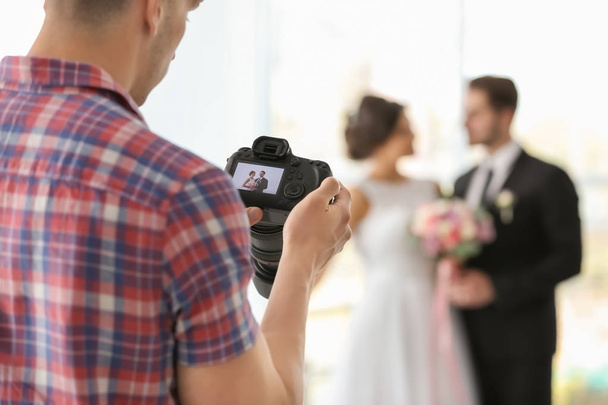 Professional photographer taking photo of wedding couple in studio - Zdjęcie, obraz