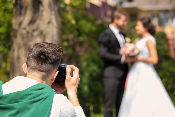 Professional photographer taking photo of wedding couple, outdoors - Foto, afbeelding