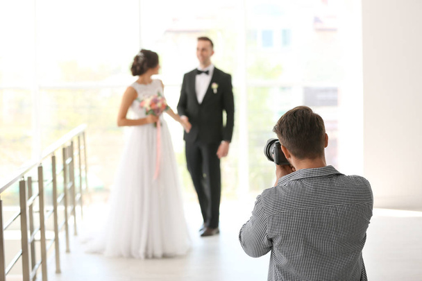 Professional photographer taking photo of wedding couple in studio - Фото, изображение